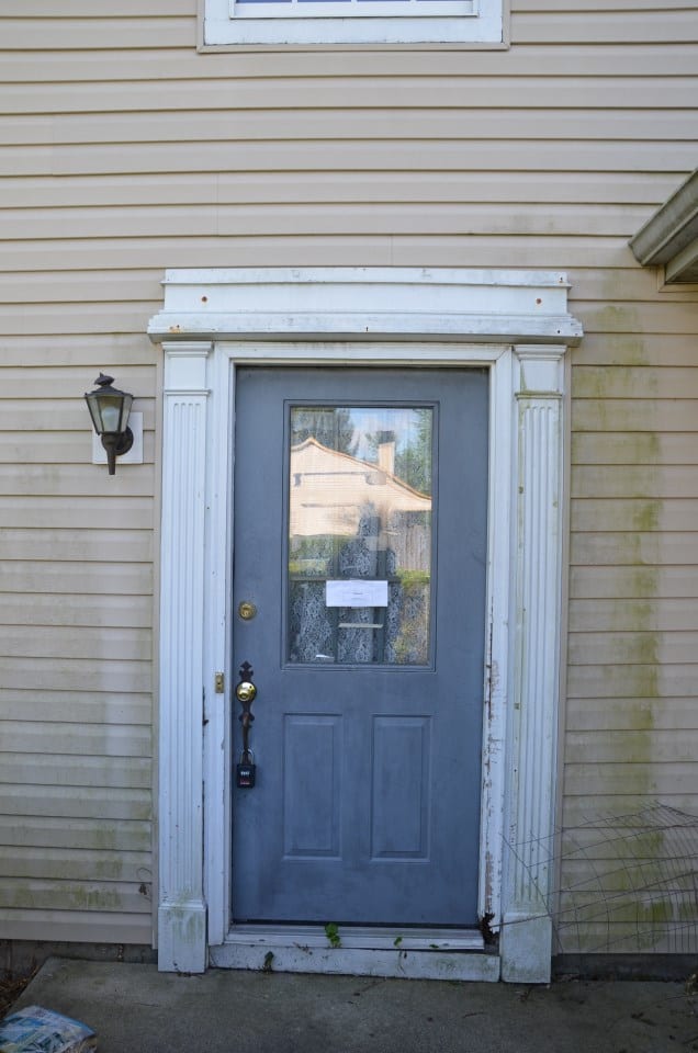 Before: a moding exterior door with mold growing on the siding