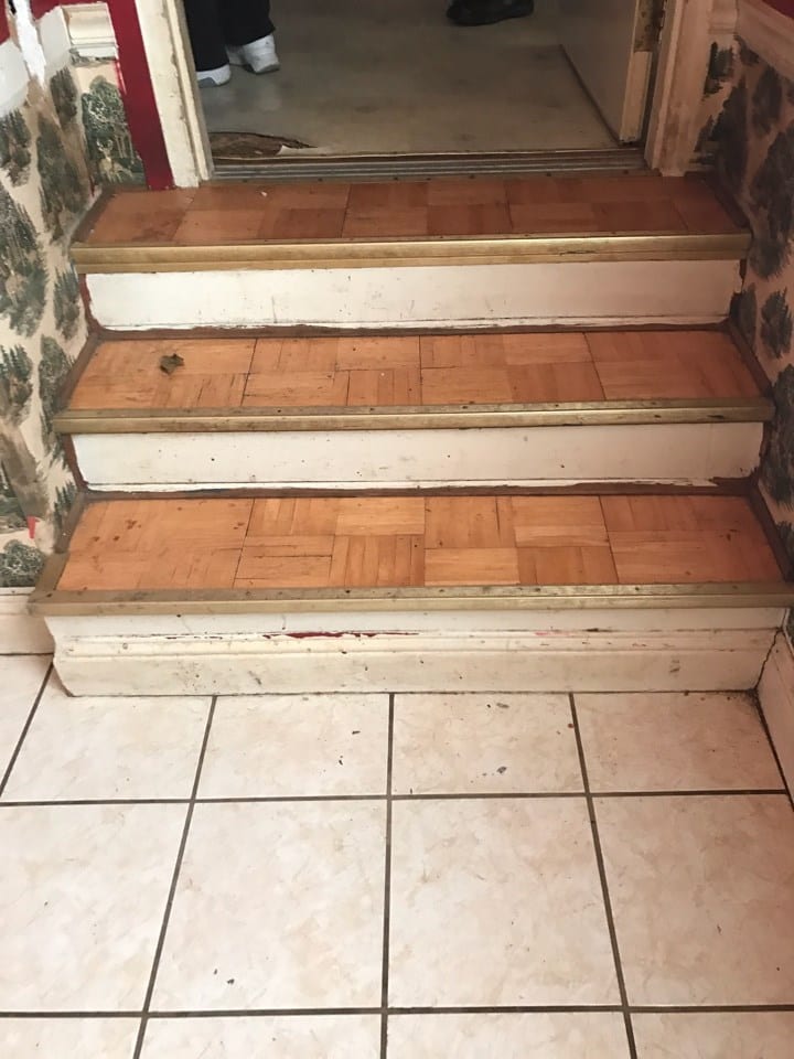 Before: Interior stairs with old tile and outdated wood laminate