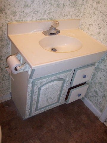 Before: a very outdated bathroom vanity with bad wallpaper